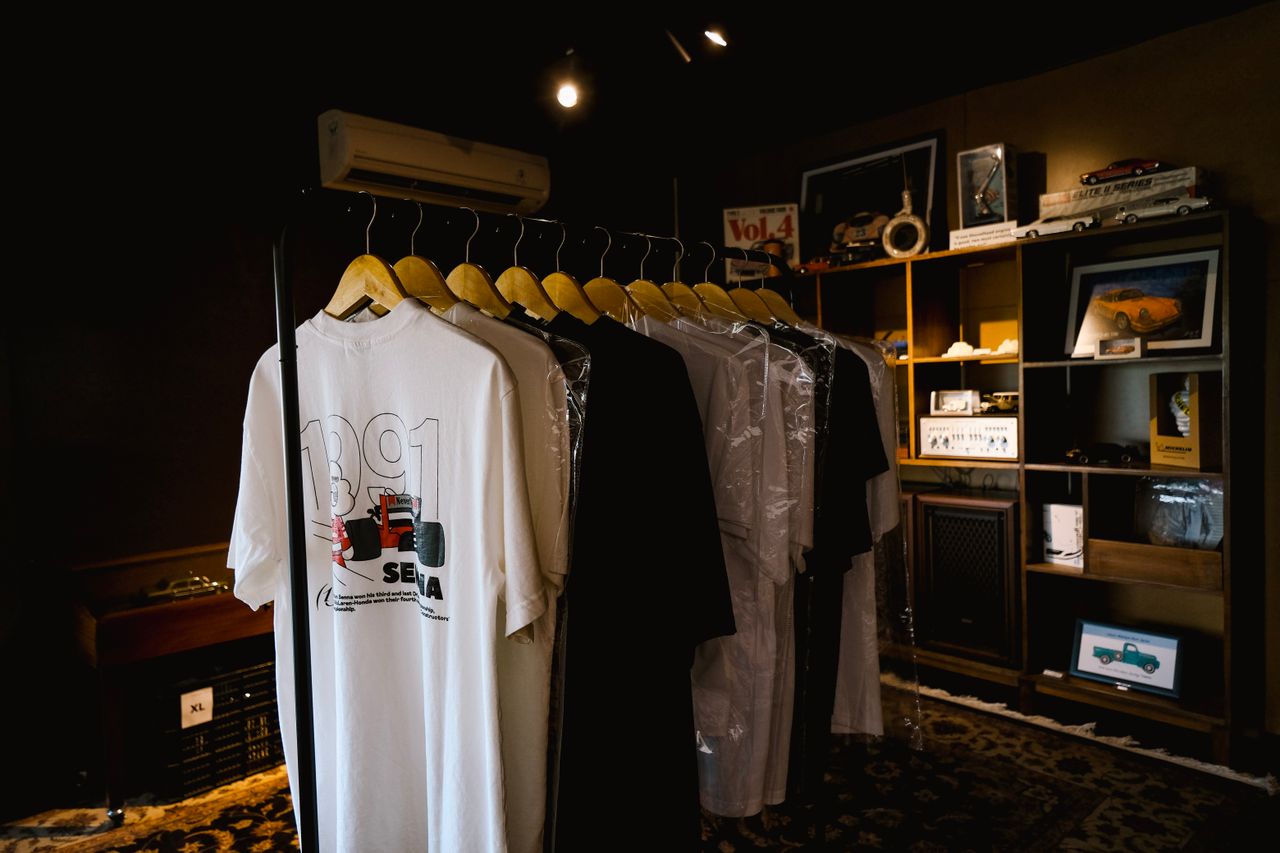 A rack of vintage t-shirts displayed in a retro-styled room with ambient lighting.